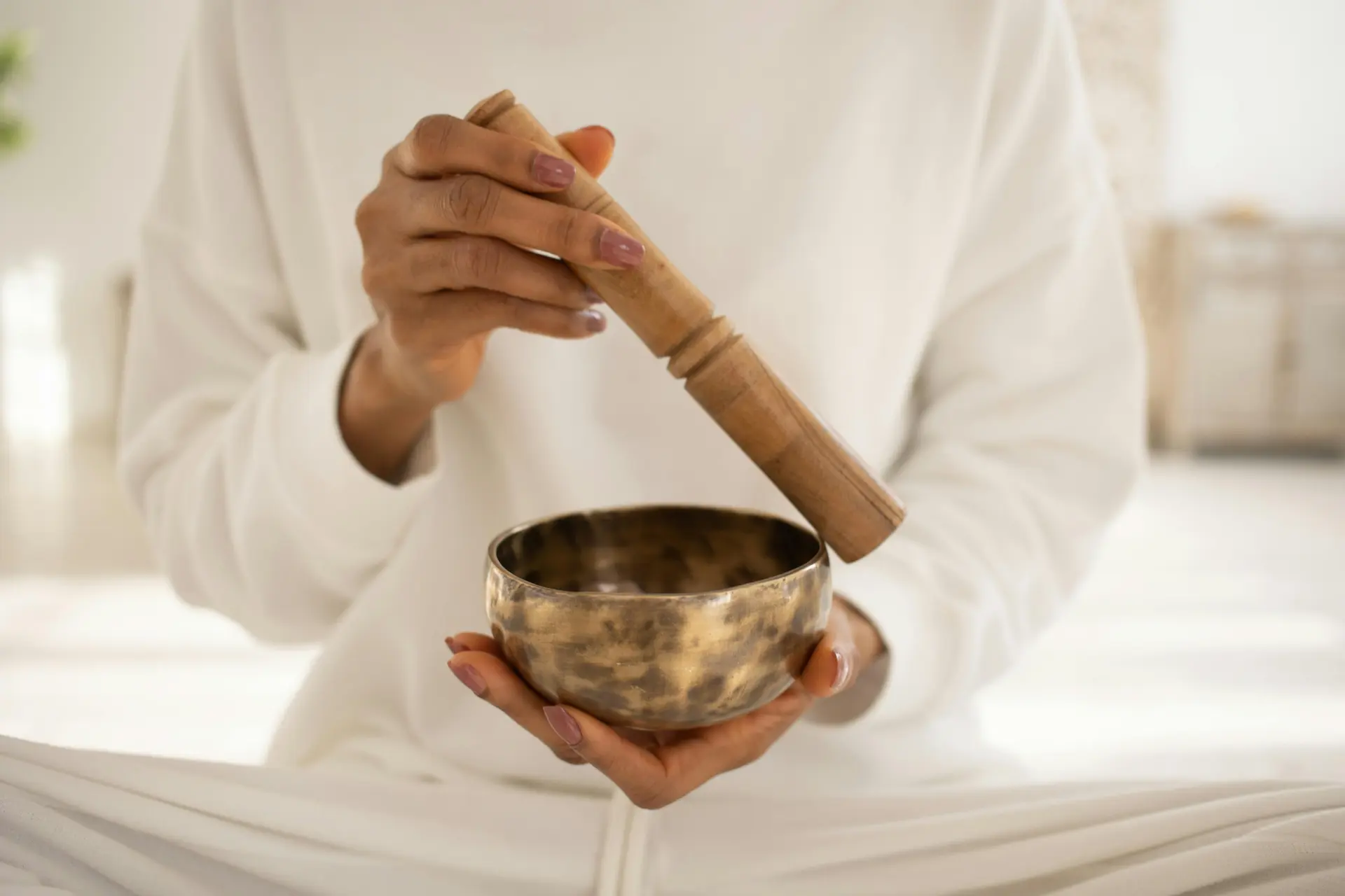 persons hands holding a meditation bowl and striker