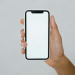 hand holding a smartphone with blank screen facing outwards