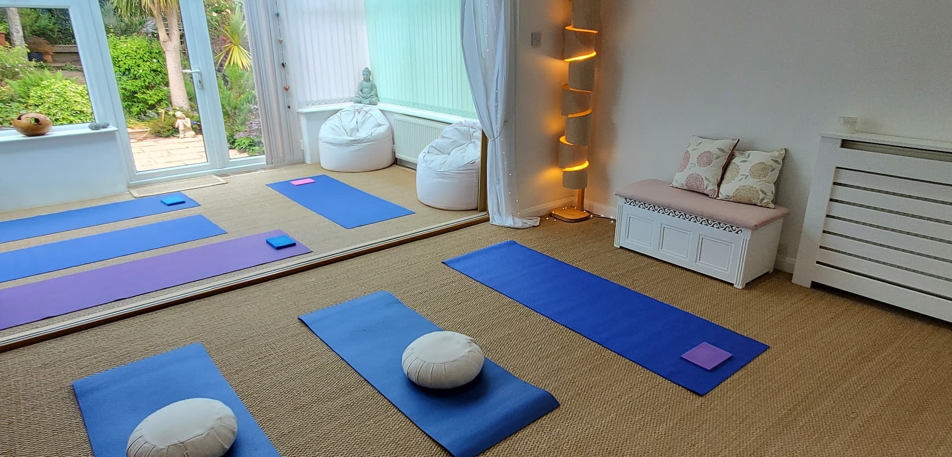 Bright, peaceful room with yoga mats laid out for a mindfulness or alexander technique class, soft lighting, and calm atmosphere